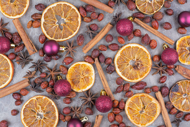 干燥在石头表面有圣诞球和玫瑰果的干橘子美味橘子闪闪发光