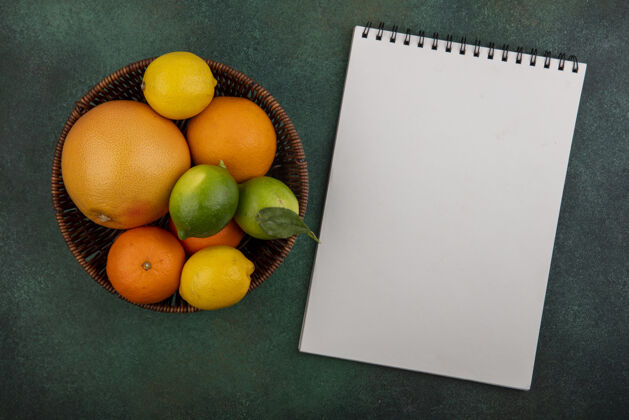 橙色顶视图复制空间葡萄柚柠檬和柠檬与绿色背景上的记事本篮子橙子葡萄柚记事本酸橙