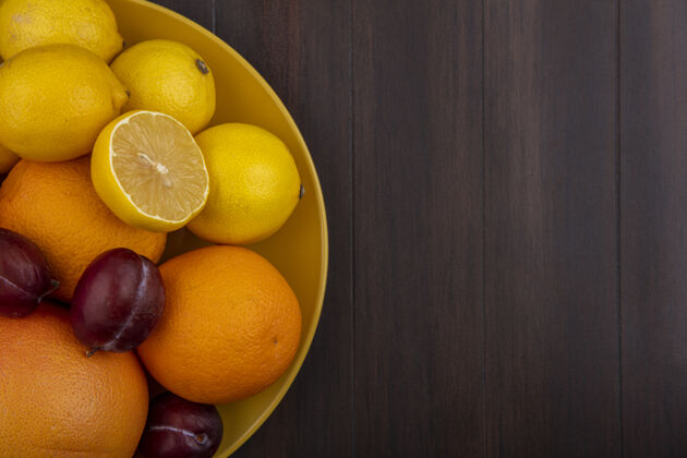 木头顶视图复制空间柠檬与橙子李子和葡萄柚在一个黄色的碗在一个木制的背景柠檬视图食物