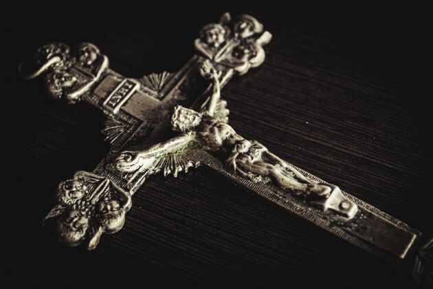 天主教一张黑色木桌子上的金属十字架特写镜头耶稣祈祷胡里