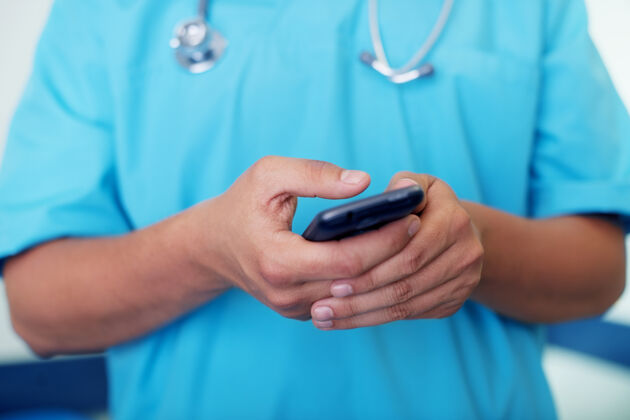 外科医生医生用手机发短信轻敲医护人员无线技术