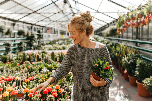 欧洲金发女人微笑着选择仙人掌 手里拿着美丽的植物植物学家公园温室