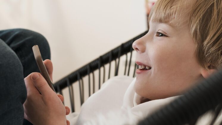 男孩侧视图笑脸男孩使用智能手机年轻业余爱好科技