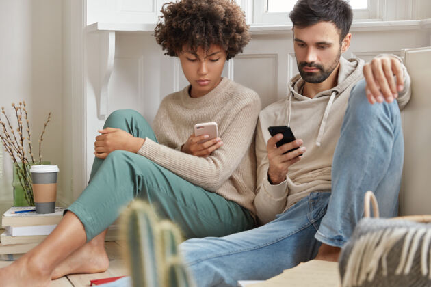 在线一对相爱的情侣一起坐在客厅的地板上房子手机青少年