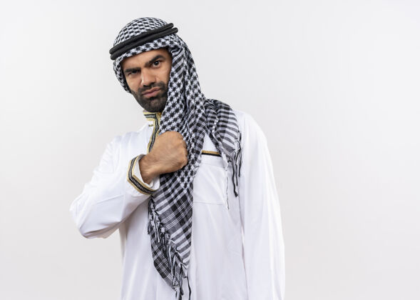 自信身着传统服装的阿拉伯男子 手捂胸口 自鸣得意 自信地站在白墙上传统胸男人