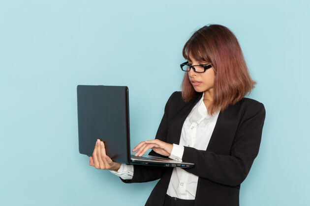使用正面图：穿着西装的女上班族在浅蓝色表面上使用笔记本电脑前台工人主管
