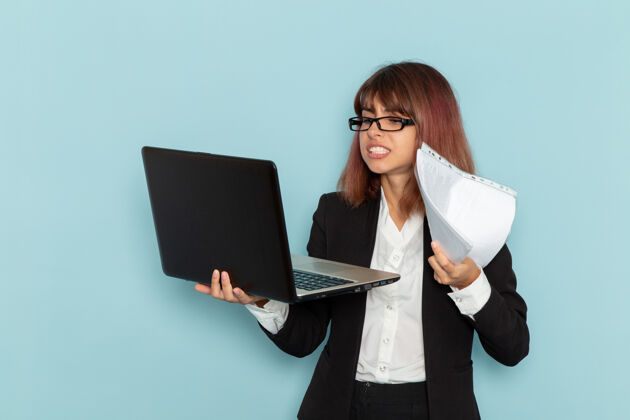使用正面图：穿着西装的女上班族手持笔记本电脑在蓝色表面西装女工作