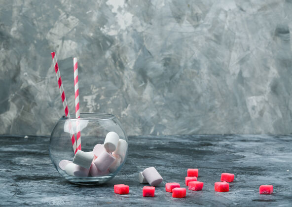 棉花糖在深蓝色和灰色的大理石表面用糖果和红色方格桌布将棉花糖和甘蔗放在罐子里 水平方向的自由空间放你的文字甘蔗糖特写糖果