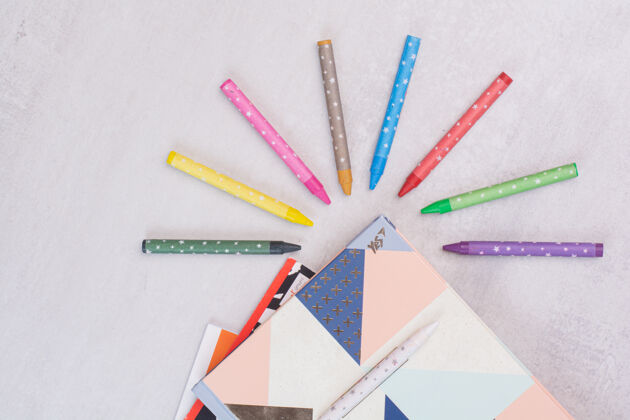 办公室一套笔记本和彩色铅笔在白色的表面彩色铅笔顶视图