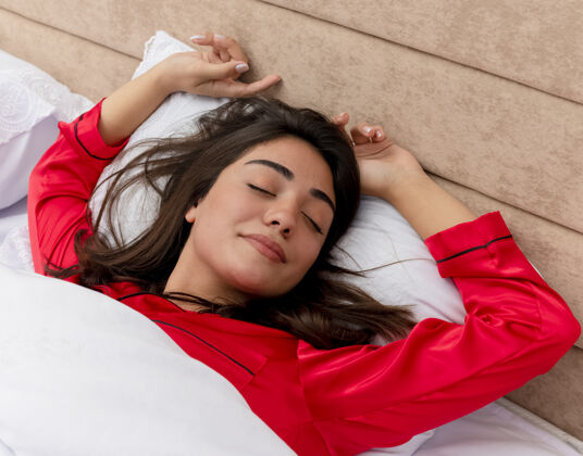 睡衣穿着红色睡衣在床上放松的年轻美女枕头卧室女人
