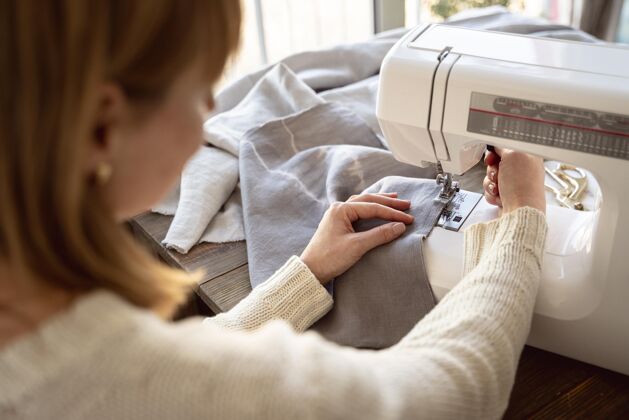 裁缝从肩上看裁缝妇女使用缝纫机细节裁缝手工