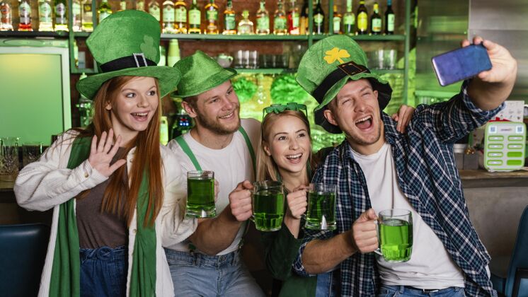 水平快乐的人们庆祝圣帕特里克节和自拍爱尔兰派对饮料