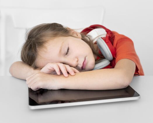 年轻人戴着耳机睡在平板电脑上的小女孩科技电子年轻人