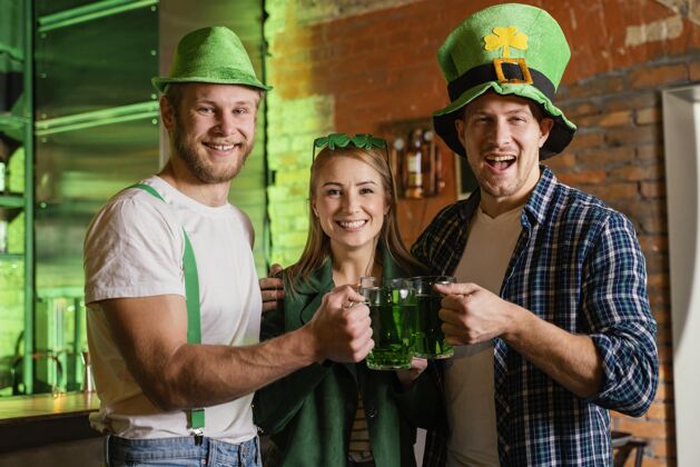 活动快乐的人们在酒吧庆祝圣帕特里克节饮料绿色帽子