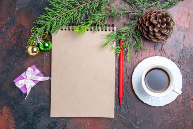 视图顶视图红色钢笔笔记本松树树枝圣诞树玩具和礼物一杯茶在暗红色的表面树枝笔记本圣诞节