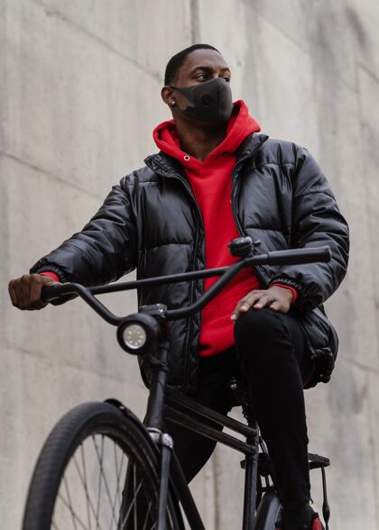 日光戴着面具骑着自行车的男人城市自行车户外