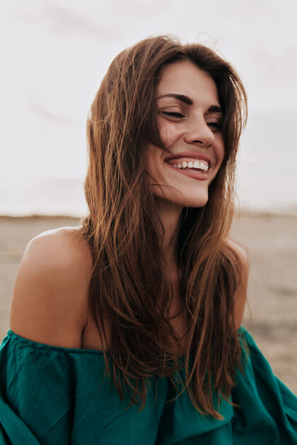 年轻快乐的微笑迷人的模特穿着露肩的裙子闭着眼睛微笑在沙滩上沙滩人海滩
