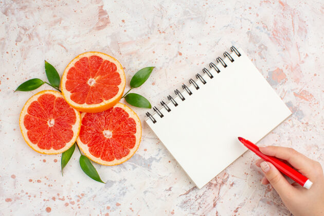维生素俯视图葡萄柚片与叶子的记事本红色标记在女性手裸体表面视图记号笔柚子
