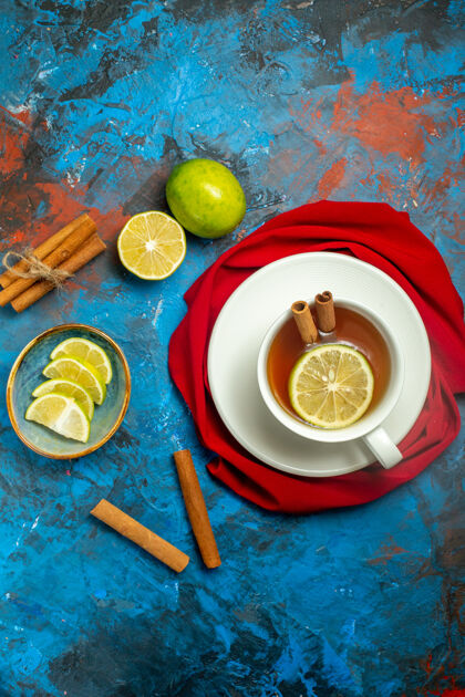 盘子俯视图一杯柠檬肉桂茶 红色披肩贴在蓝红色的表面柑橘顶部早餐