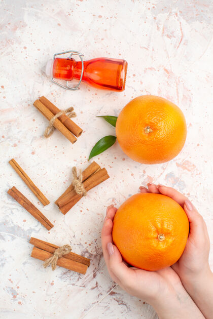 多汁顶视图新鲜橙子肉桂棒在女性手瓶明亮的表面肉桂柑橘明亮