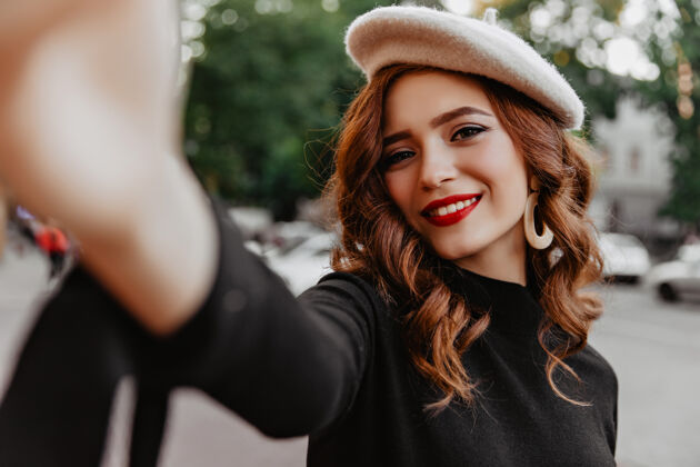 微笑11月的一天 一个长着姜黄色头发的漂亮法国女孩在街上摆姿势优雅的红唇白种女人在街上自拍的户外镜头季节享受自拍