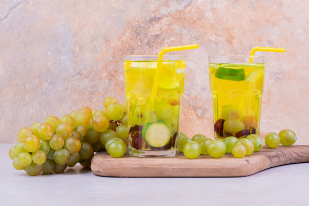 美味绿葡萄和两杯果汁放在木板上饮料灯光食物