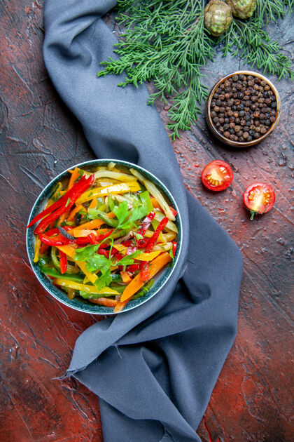 树枝顶视图蔬菜沙拉在碗黑胡椒冷杉枝群青蓝色披肩在暗红色的桌子上一餐盘子碗