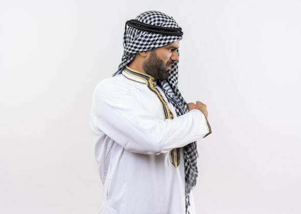 手指一个穿着传统服装的阿拉伯男人不高兴地站在一边 用手指着墙穿背站