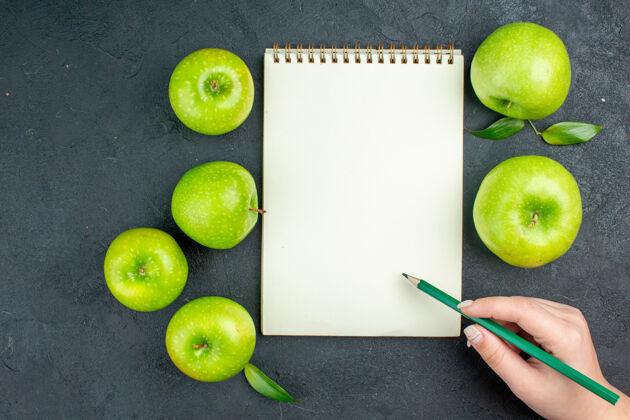 苹果顶视图笔记本绿色苹果绿色铅笔在女性手中黑暗的表面酸橙关键酸橙柑橘