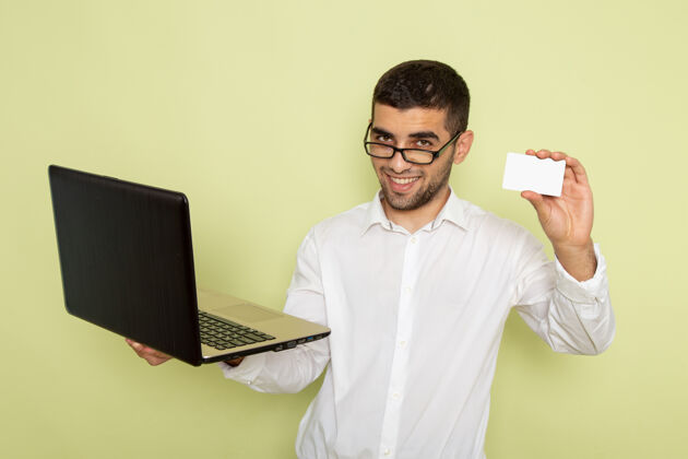 衬衫身穿白衬衫的男上班族正拿着笔记本电脑和卡片站在绿色的墙上持有笔记本电脑前面