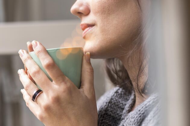 斯堪的纳维亚一个女人拿着一杯咖啡看着外面房子室内女人