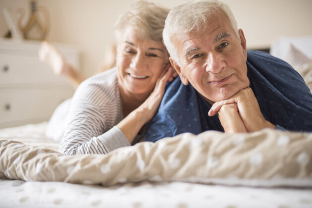 躺着快乐的老年夫妇躺在床上活力休息卧室