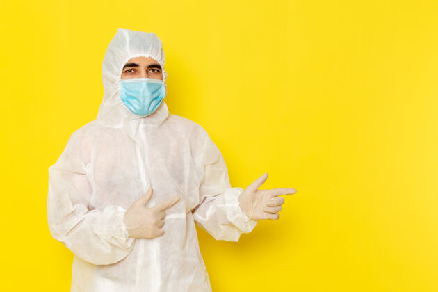 护理身穿白色防护服 带面罩 浅黄色墙壁的男性科学工作者正面图工人脸危险