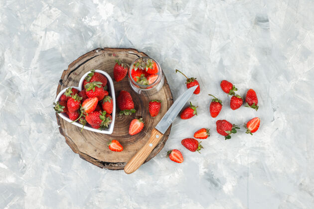 食物在深蓝色大理石表面的圆形柳条垫子上高角度观看一碗草莓水平维生素成熟吃