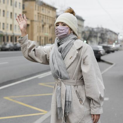 大流行戴着医用面罩在城里招手的女人人类防护流行病