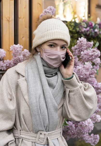 人类戴着医用口罩打电话的女人防护智能手机病毒