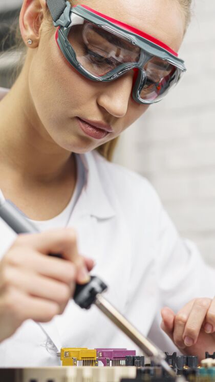 技术员带烙铁和护目镜的女技师科学家智力研究