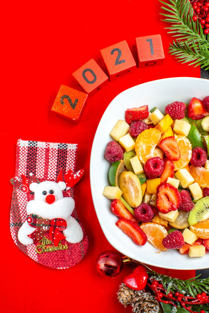 树枝收集新鲜水果的半张照片放在餐盘上装饰配件杉木树枝和数字和圣诞袜放在红色餐巾上餐巾纸托盘一半
