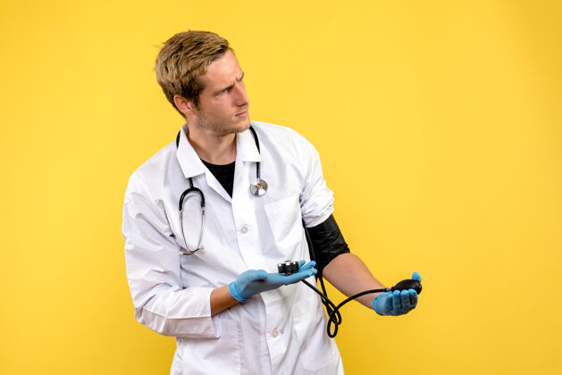 正面前视图男性医生测量他的压力对黄色背景病毒的健康医生比赛球员医学