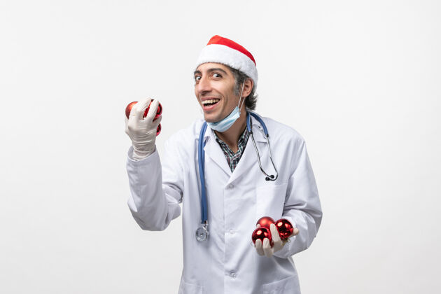 冠状病毒正面图：男医生拿着玩具在白墙上-健康病毒情感听诊器外套玩具