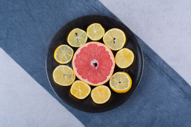 食用把新鲜的柚子和柠檬片放在黑色盘子里葡萄柚柑橘切片