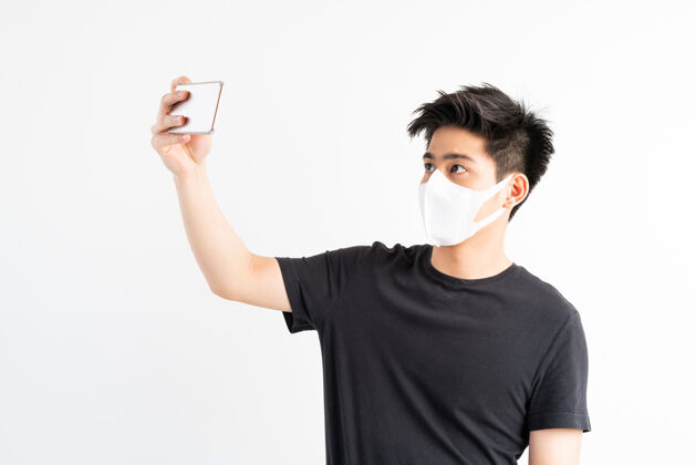 传播亚洲男子戴口罩保护冠状病毒冠状病毒-19使用智能手机在隔离室一天男性人