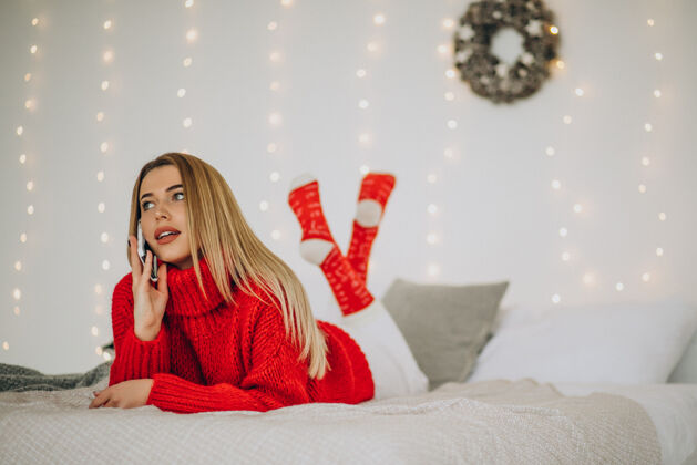 美丽在圣诞节用电话的年轻女人通信礼物灯光