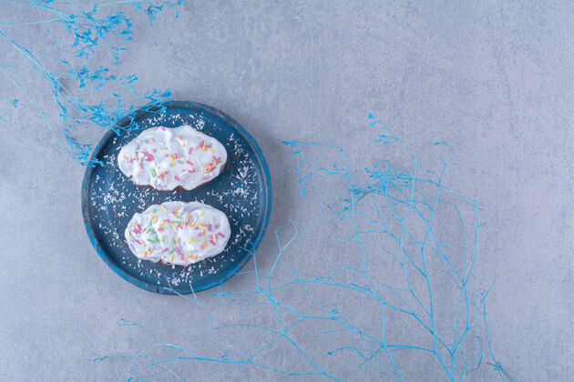 食品两个新鲜的甜纸杯蛋糕 蓝色木板上有五颜六色的洒点和奶油奶油甜食面包房