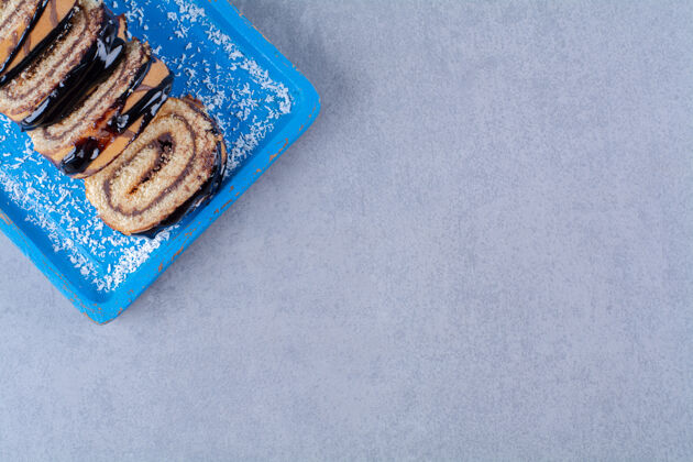 卷一块蓝色的木板 上面是巧克力糖浆切成的甜面包卷食品木材糖果