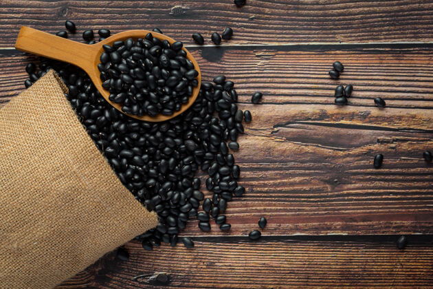 作物黑豆放在小木勺旁边的麻袋里装满了黑豆草药食品营养