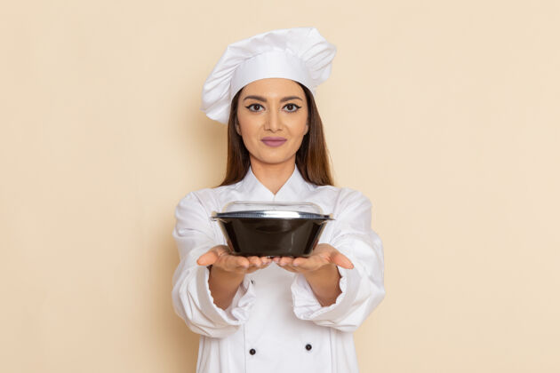 膳食身穿白色厨师服的年轻女厨师正拿着黑碗站在白墙上厨房年轻工作