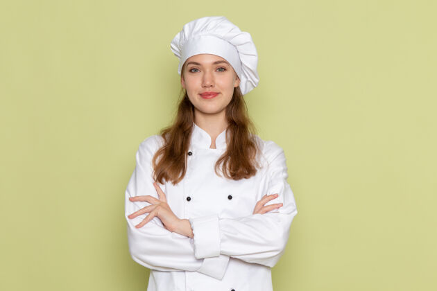 淋浴帽身着白色厨师服的女厨师在绿色墙壁上微笑着摆姿势成人前面帽子