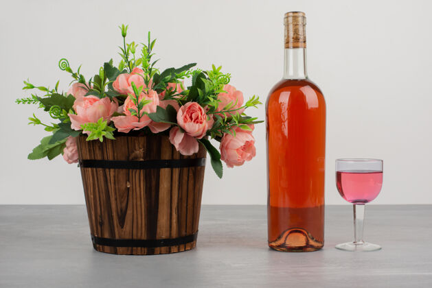 葡萄酒美丽的花束和一瓶玫瑰红酒摆在灰色的桌子上玻璃叶子自然