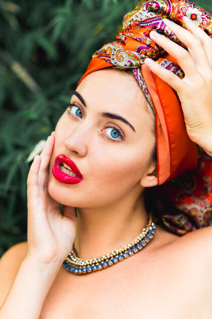 姿势美丽的女人 完美的妆容和橙色的头巾 红色的大嘴唇 蓝色的眼睛 手放在头上魅力温柔感性